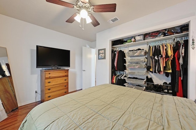 bedroom featuring visible vents, a ceiling fan, wood finished floors, a closet, and baseboards