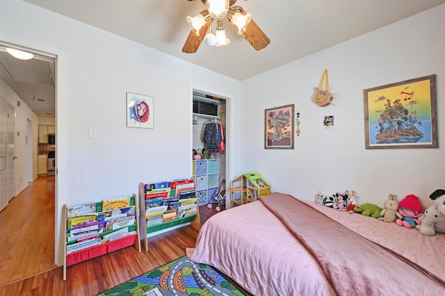 bedroom with attic access, wood finished floors, a closet, and ceiling fan