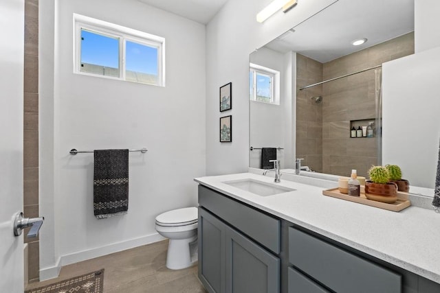 bathroom featuring vanity, toilet, plenty of natural light, and tiled shower