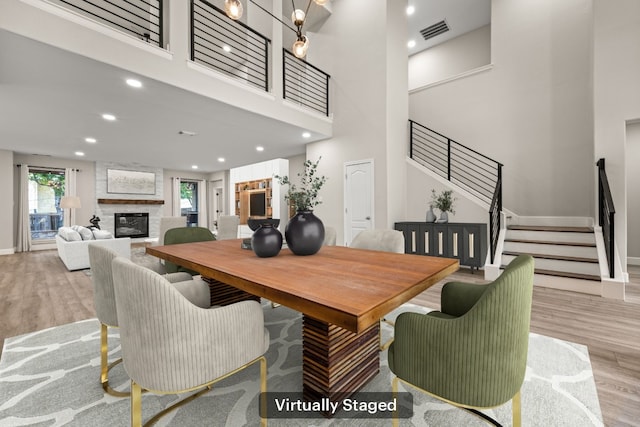 dining area featuring visible vents, stairs, a towering ceiling, and wood finished floors