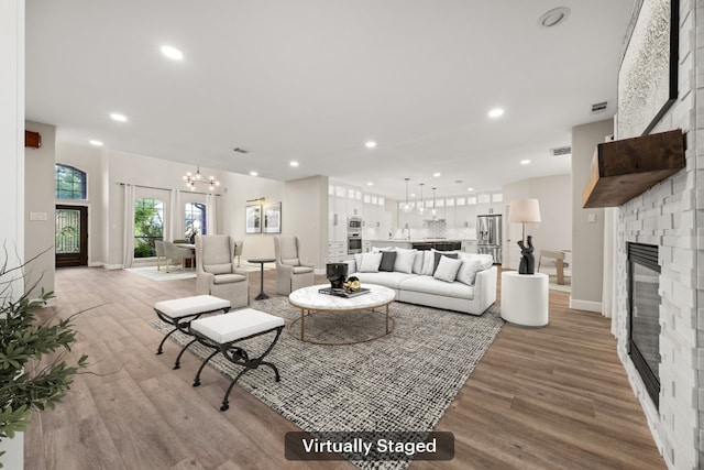 living area with visible vents, recessed lighting, light wood-style floors, a large fireplace, and a chandelier