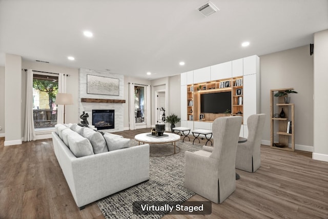 living area with wood finished floors, recessed lighting, a fireplace, and visible vents