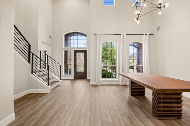 foyer entrance featuring visible vents, wood finished floors, stairway, baseboards, and a chandelier