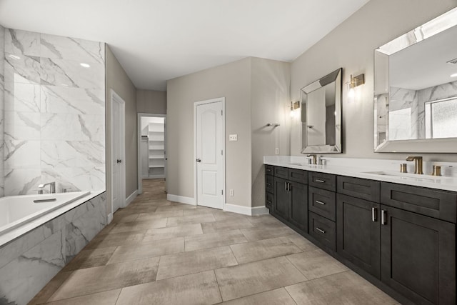 bathroom with double vanity, a bath, baseboards, and a sink