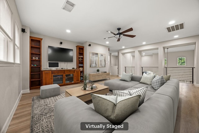 living room with visible vents, baseboards, light wood-style floors, and ceiling fan