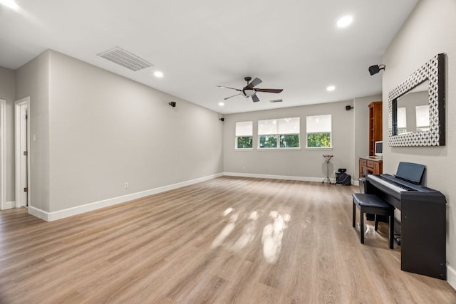 living room with visible vents, baseboards, light wood-type flooring, and ceiling fan