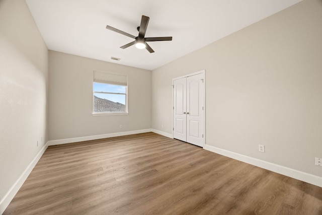 unfurnished room featuring visible vents, baseboards, and wood finished floors