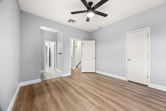 unfurnished bedroom featuring ceiling fan, light wood-style floors, visible vents, and baseboards