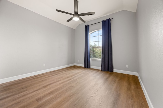 spare room with lofted ceiling, wood finished floors, a ceiling fan, and baseboards