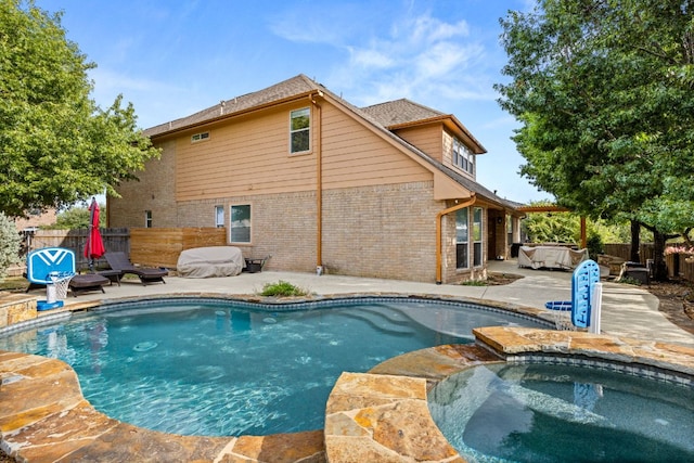 view of pool with a patio area, a pool with connected hot tub, and fence