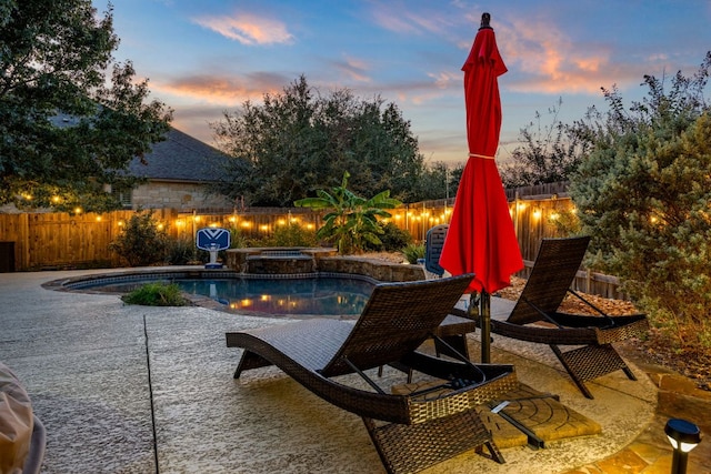 pool at dusk with a patio area, a fenced backyard, a fenced in pool, and an in ground hot tub