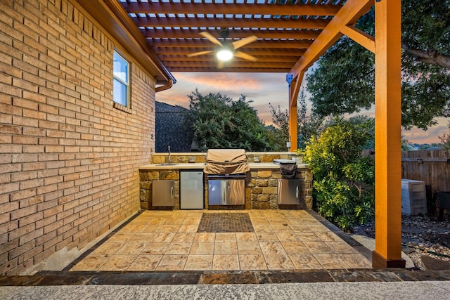 view of patio featuring an outdoor kitchen, fence, a pergola, and a sink