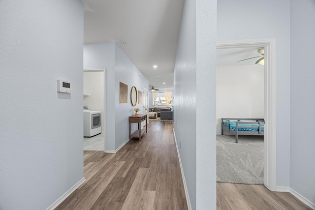 hallway featuring baseboards, washer / dryer, and wood finished floors