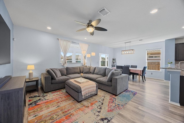 living area featuring visible vents, baseboards, recessed lighting, light wood-style flooring, and a ceiling fan