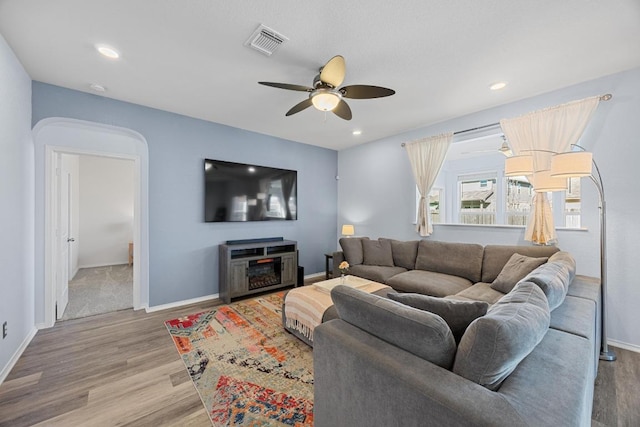 living room with visible vents, arched walkways, wood finished floors, and a ceiling fan