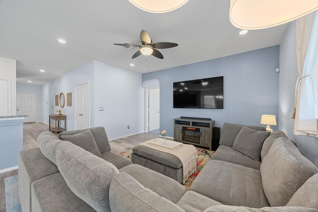 living area featuring baseboards, light wood-type flooring, recessed lighting, arched walkways, and a ceiling fan