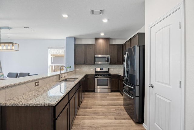 kitchen with visible vents, light wood finished floors, a sink, dark brown cabinets, and appliances with stainless steel finishes