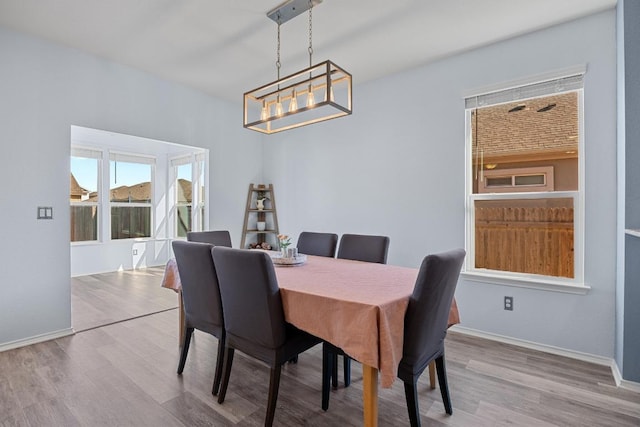 dining space with baseboards, an inviting chandelier, and wood finished floors