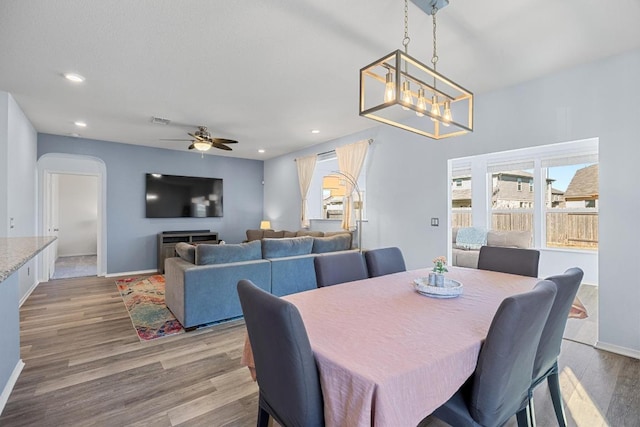 dining room with visible vents, ceiling fan with notable chandelier, recessed lighting, wood finished floors, and arched walkways