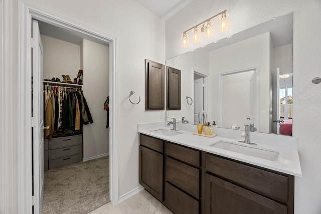 full bath featuring a walk in closet, double vanity, baseboards, and a sink