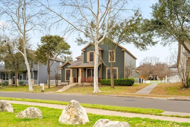 view of front of house with a front lawn, fence, and covered porch