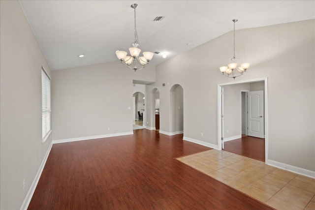 157 Mcgarity, Kyle, TX 78640 - empty room featuring a chandelier, arched walkways, wood finished floors, high vaulted ceiling, and baseboards