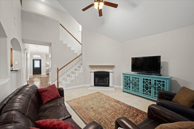 157 Mcgarity, Kyle, TX 78640 - carpeted living area featuring a ceiling fan, stairs, arched walkways, high vaulted ceiling, and a fireplace with raised hearth