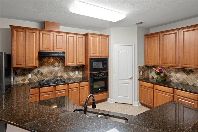 kitchen featuring visible vents, black appliances, a sink, ventilation hood, and light tile patterned floors