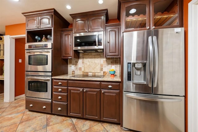 kitchen with backsplash, glass insert cabinets, light stone counters, recessed lighting, and appliances with stainless steel finishes