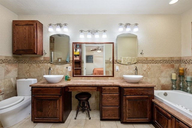 bathroom with tile patterned flooring, double vanity, a garden tub, and a sink