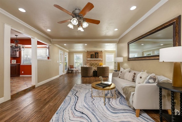 living area featuring baseboards, ceiling fan with notable chandelier, wood finished floors, and ornamental molding