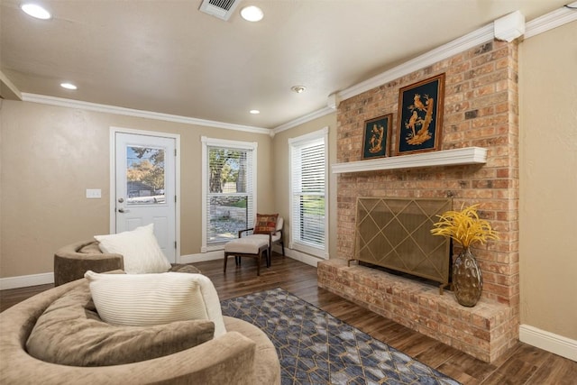 living area featuring visible vents, baseboards, ornamental molding, a fireplace, and wood finished floors