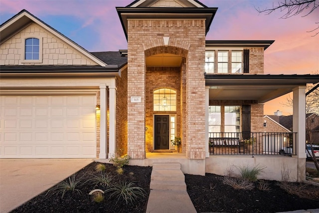 view of front facade with concrete driveway, an attached garage, covered porch, and brick siding