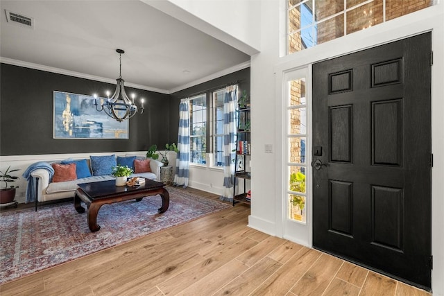 entrance foyer featuring visible vents, wood finished floors, crown molding, and a chandelier