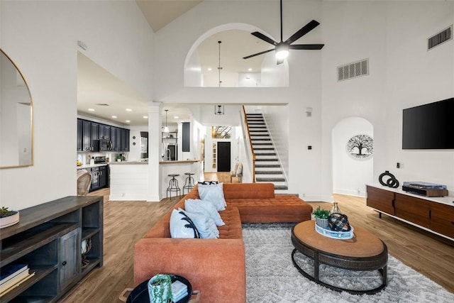 living room featuring visible vents, stairs, light wood-type flooring, and ceiling fan