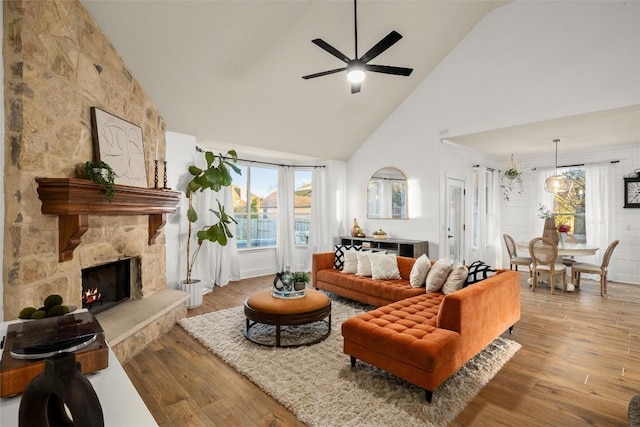 living area featuring ceiling fan, high vaulted ceiling, wood finished floors, and a fireplace