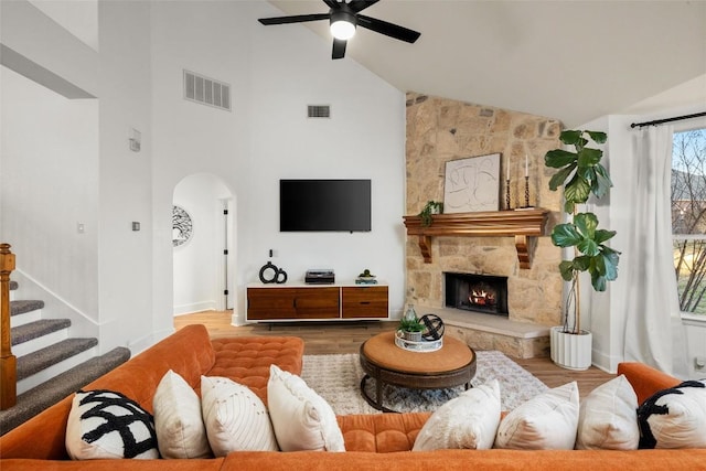 living area with a ceiling fan, wood finished floors, arched walkways, and visible vents