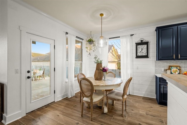 dining space with wood finish floors, baseboards, and crown molding