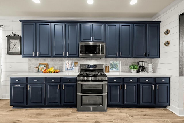 kitchen featuring wood tiled floor, blue cabinetry, stainless steel appliances, light countertops, and backsplash