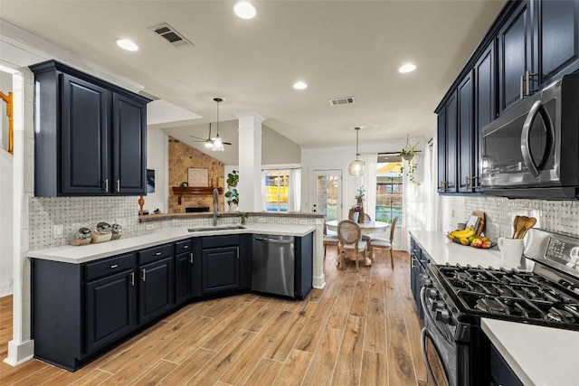 kitchen featuring visible vents, a sink, appliances with stainless steel finishes, a peninsula, and lofted ceiling