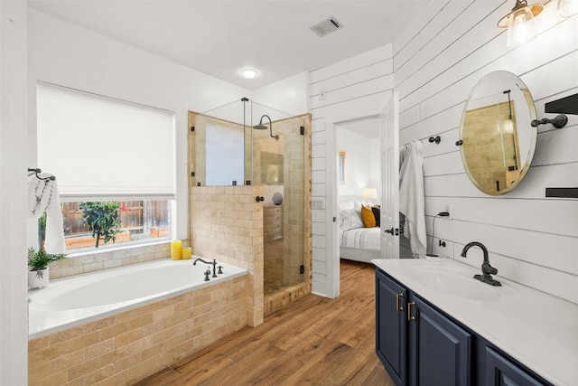 bathroom featuring a shower stall, a garden tub, wood finished floors, and visible vents