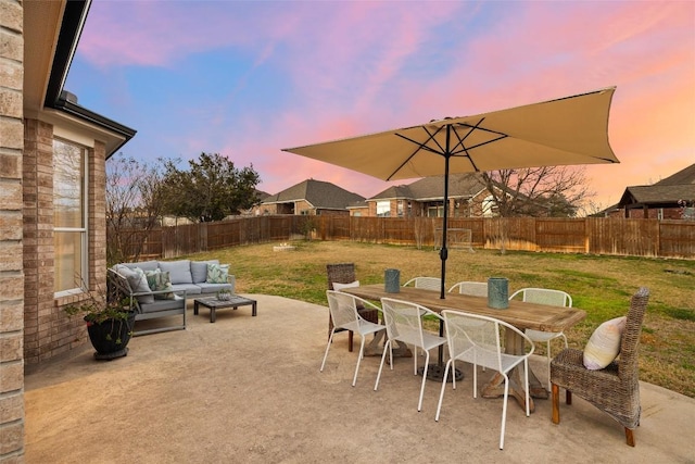 patio terrace at dusk featuring outdoor dining space, a yard, a fenced backyard, and an outdoor hangout area