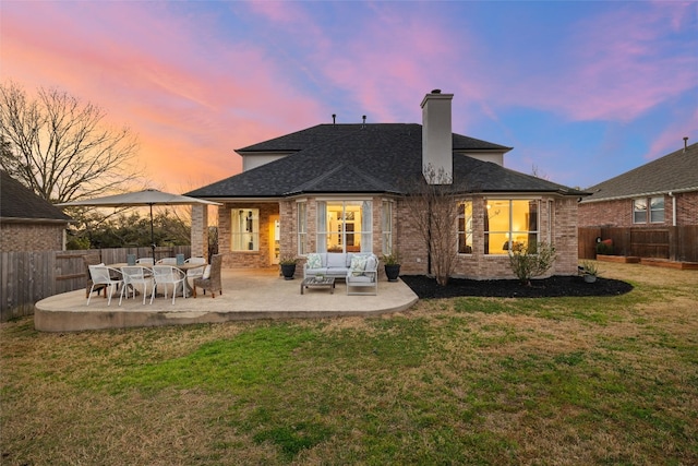 back of house at dusk featuring a yard, an outdoor hangout area, a fenced backyard, and a patio area