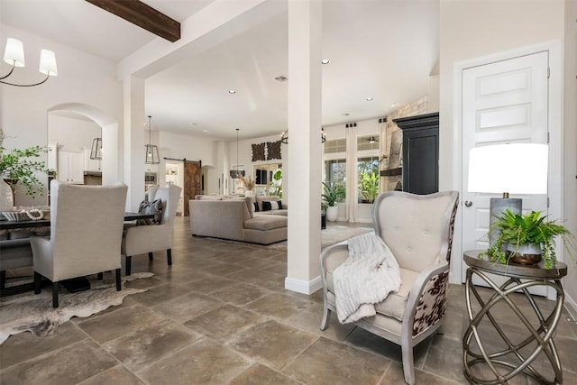 living room featuring arched walkways, beam ceiling, recessed lighting, stone finish flooring, and baseboards