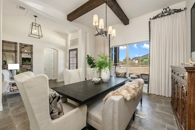 dining space with visible vents, beamed ceiling, stone finish floor, arched walkways, and an inviting chandelier