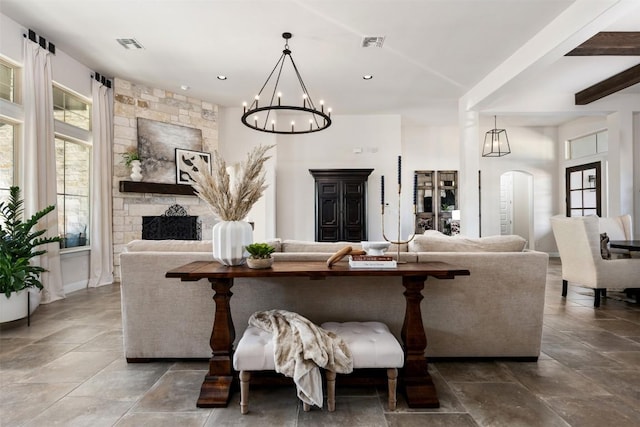 living room featuring a chandelier, arched walkways, a stone fireplace, and recessed lighting