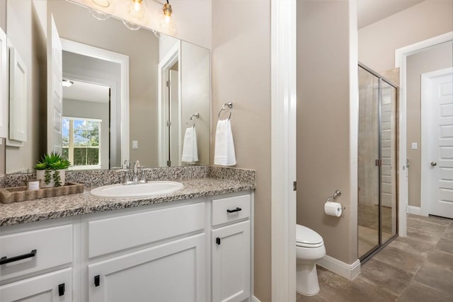 bathroom with a shower stall, toilet, vanity, and baseboards