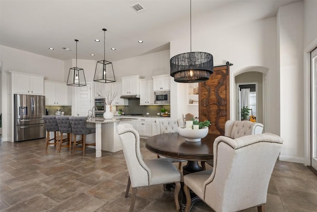 dining space featuring visible vents, baseboards, recessed lighting, a high ceiling, and arched walkways