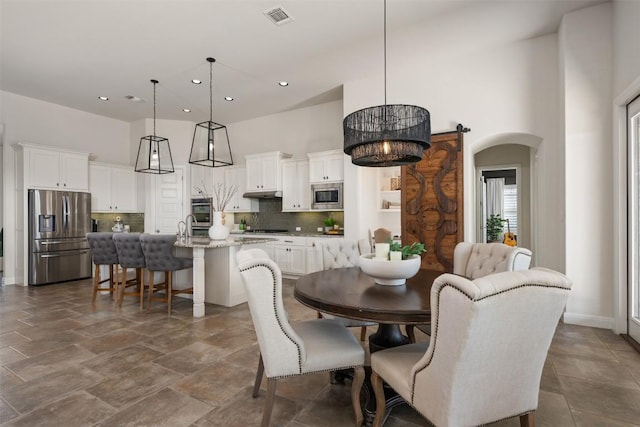 dining room with recessed lighting, arched walkways, and a high ceiling