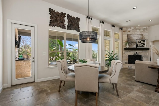 dining space with a stone fireplace, plenty of natural light, baseboards, and visible vents